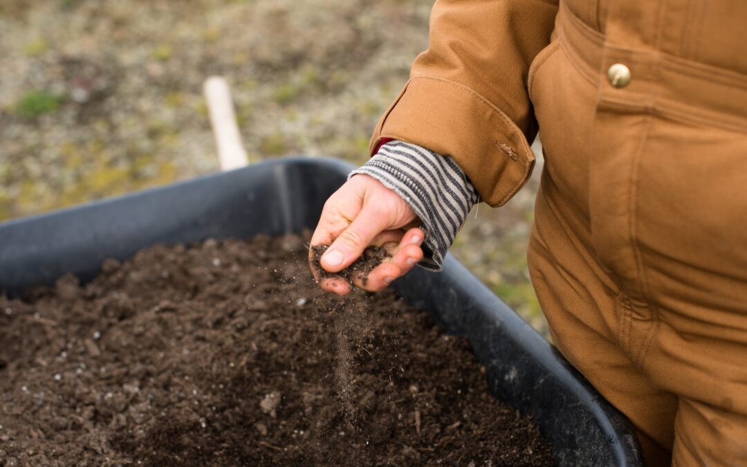 person in yellow jacket holding black soil